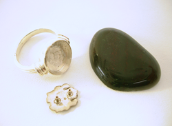 Photo of a white gold ring, a white gold emblem, and a rough piece of Bloodstone.