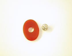 This shows an oval orangy-red colored Carnelian cabochon with a diamond mounted in a gold tube sitting next to it.