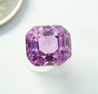 Photo of a poorly cut emerald cut pink Sapphire which is windowed.