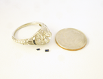 An antique diamond ring and 2 very tiny blue Sapphires sitting next to the ring.