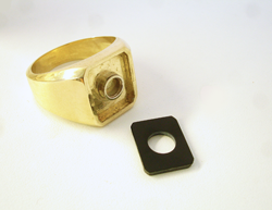 Photo of a gold men's ring with a round tube set in the middle and also an emerald cut Black Jade.