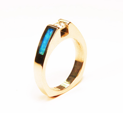 A round diamond in the center of a simple white gold ring and a narrow rectangular Opal inlaid on each side.