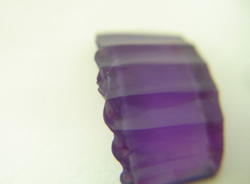 Photo shows one of the synthetic Amethyst carvings from the same bracelet with a chip in it.