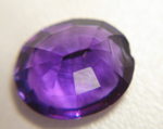 Photo of a purple oval Amethyst with a large chip in the pavilion.