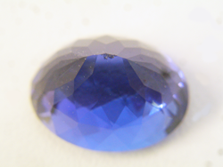 An oval blue Tanxanite face down showing chips on the culet.