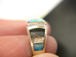 Photo of a ring with one Opal inlay and a blank area where 2 Opal inlays have fallen out.