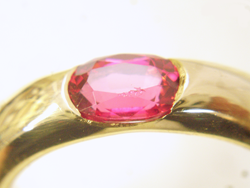 Photo of a pink Spinel with chips on the table and star facets while it is in the ring.