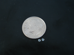A picture of two tiny Aquamarine cabochons next to a dime.