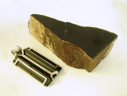A chunk of rough black jade next to the pendant with the broken black onyx.