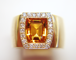 A bright orangy Yellow citrine in a ring surrounded by diamonds.