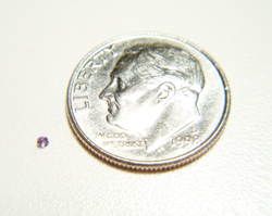 Picture of a very tiny round Amethyst next to a dime for size comparison.