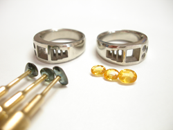 2 white gold rings and 3 blue sapphires glued to dop sticks and 3 yellow sapphires.