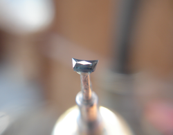 Shows the Sapphire on the dop stick in the faceting machine.