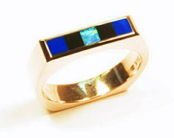 Ring inlaid with 5 inlays. 2 squares are Lapis. 2 are black Onyx. And the center square is Opal.