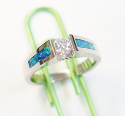 A round diamond in the center of a simple yellow gold ring and a narrow rectangular Opal inlaid on each side.