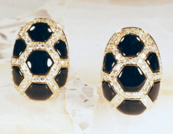 A pair of gold earrings which are inlaid with several hexagonal black Onyx inlays which have slight domes on the top.