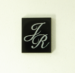 Photo of a rectangular black Onyx stone with the initials J R in white which were made with a laser.