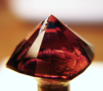 Photo of a pink Tourmaline with a large chip in the culet of the pavilion.