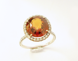 Photo of a diamond ring with an orange Spessartite Garnet center stone.